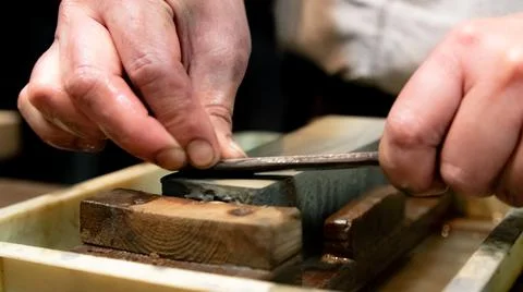 Master swordsmith is sharpening knife on grindstone with water Stock-Fotos