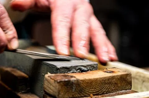 Master swordsmith is sharpening knife on grindstone with water Foto stock