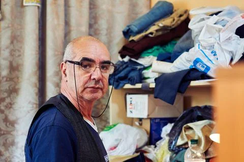 Master tailor in glasses in a workshop for tailoring and repairing clothes Stock Photos