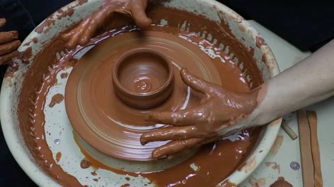 Master teaches apprentice how to make a clay pot on a potter's wheel Stock Footage 188490076
