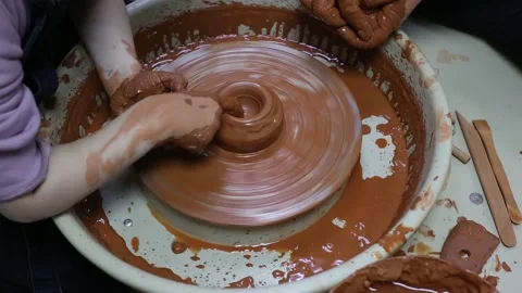 Master teaches apprentice how to make a clay pot on a potter's wheel Stock Footage 188494562