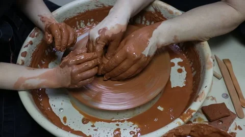 Master teaches apprentice how to make a clay pot on a potter's wheel Stock Footage 188731901