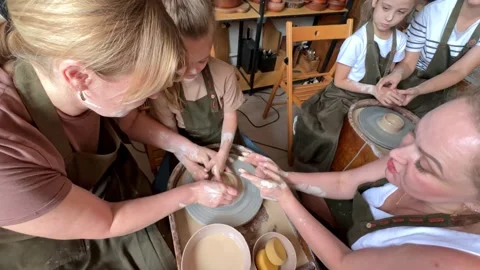 Master teaches children and their moms to make a clay jug potter's wheel Stock Footage 277793822