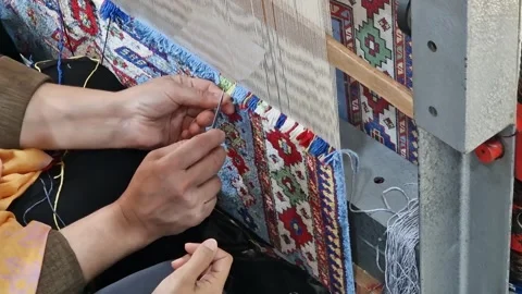 Master teaching student the art of traditional carpet weaving. Stock Footage 335981495