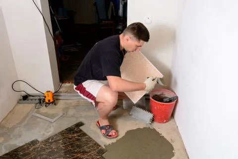 The master tile smears the mucilage solution on the marble tile Fotos de archivo