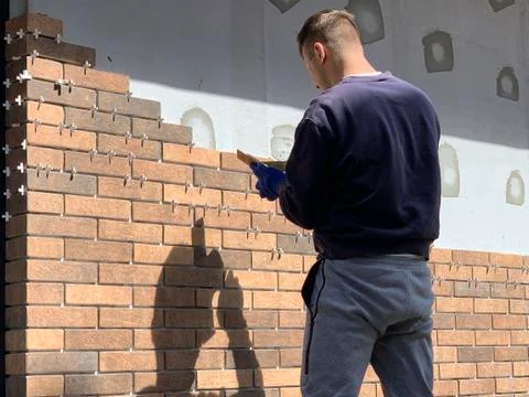 The master tiled the facade of the house. Builders adorn the walls of a brick Stock Photos