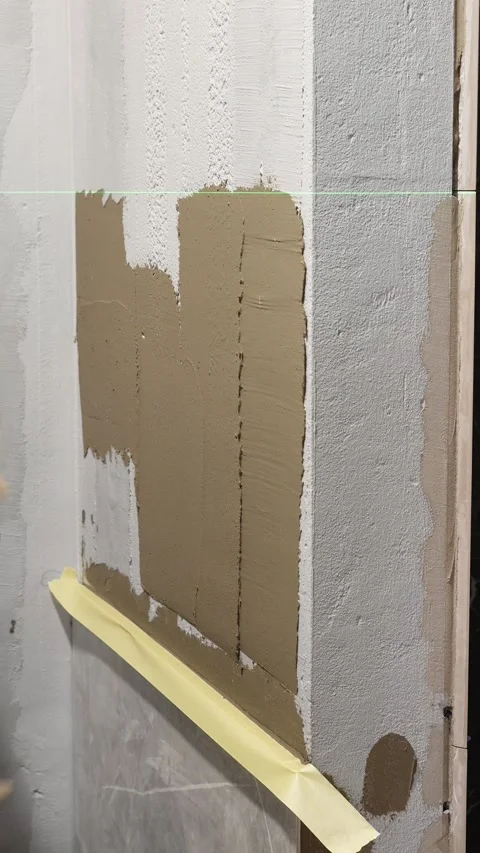 Master tiler applies tile adhesive with a spatula to the wall Stock Footage 317902261