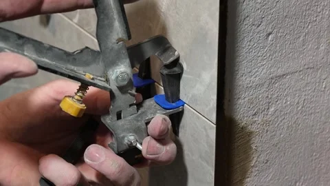 The master tiler inserts the blades into the tile leveling system Stock Footage 317901819