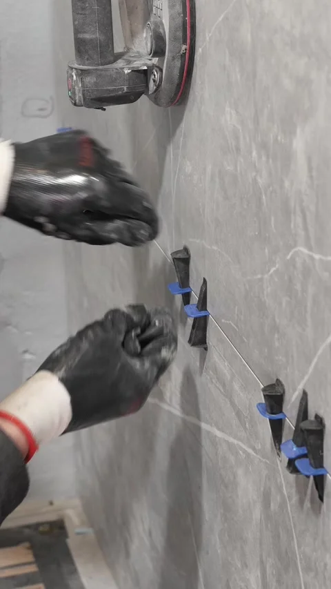 The master tiler inserts the blades into the tile leveling system Stock Footage 317902326