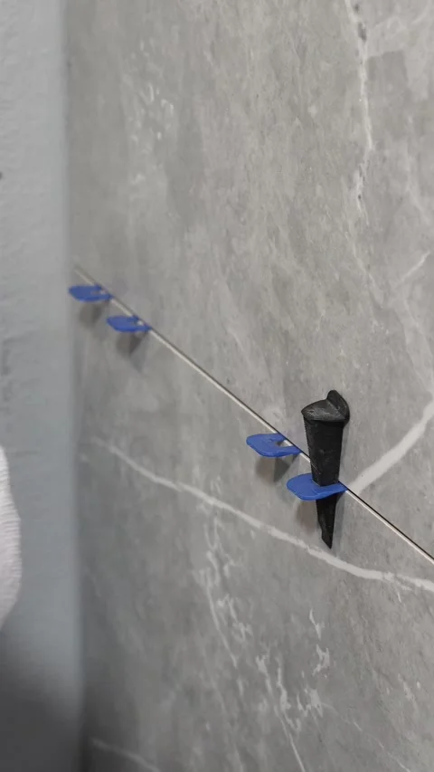 The master tiler inserts the blades into the tile leveling system Stock Footage 317902332