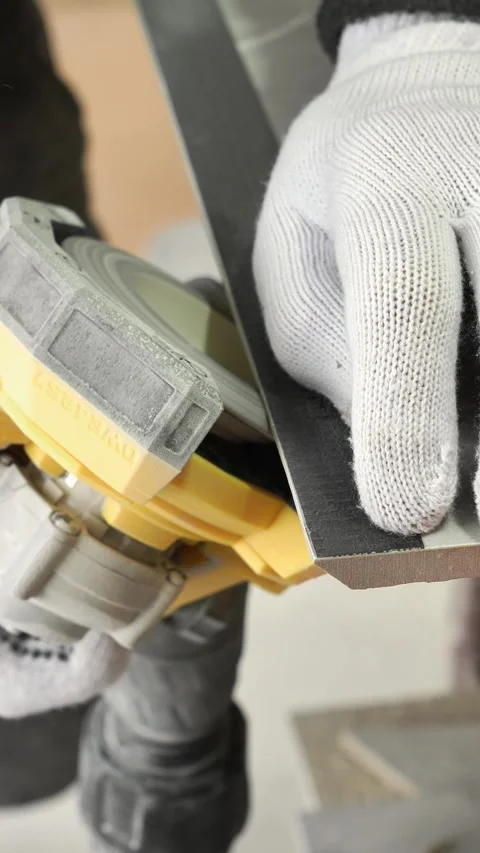Master tiler sands grey tiles with a power tool before laying Stock Footage 317902455