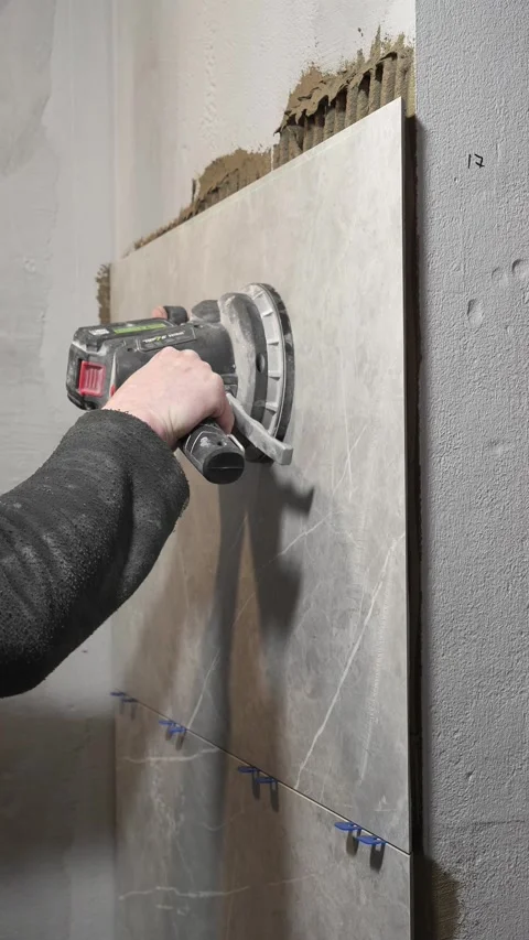 Master tiler vibrates tiles with professional power tool Stock Footage 317902329