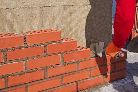 The master with the trowel puts the red brick. Stock Photos