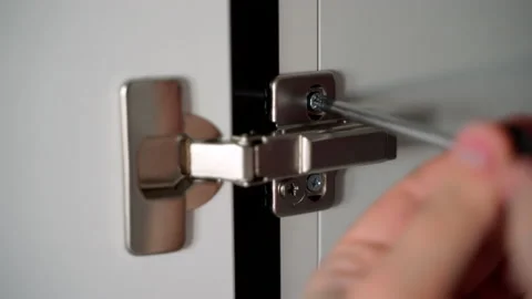 Master twists the screw of the hinge of the Cabinet door in the kitchen Stock Footage 153292633