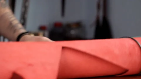 Master unwinds a roll of red leather for the production of leather goods 動画素材 88831688