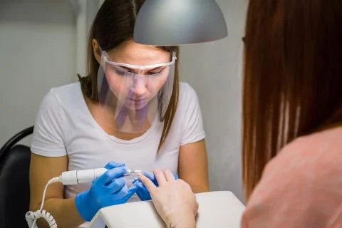 The master uses an electric machine to remove the nail polish Stock Photos