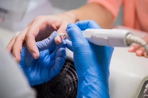 The master uses an electric machine to remove the nail polish Stock Photos
