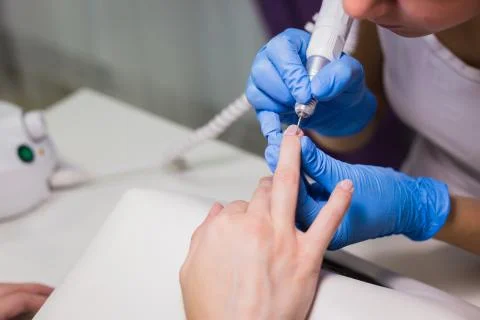 The master uses an electric machine to remove the nail polish Stock Photos