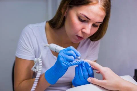 The master uses an electric machine to remove the nail polish Stock Photos