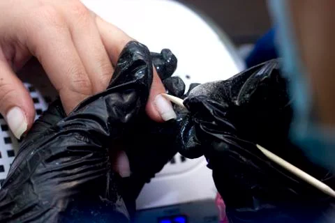 Master uses a machine and a cutter to process the girl`s nails Stock Photos