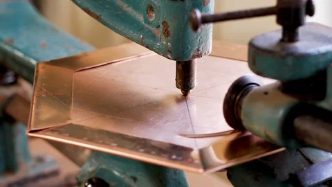 The master, using a copper sheet cutting machine, cuts a circle into the product Stock Footage 124471840