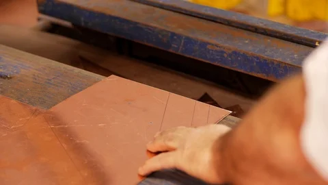 The master using a cutter, cuts the shape of the product from a sheet of copper Stock Footage 124464446