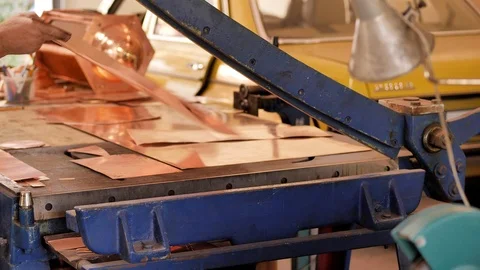 The master using a cutter, cuts the shape of the product from a sheet of copper Stock Footage 124464661