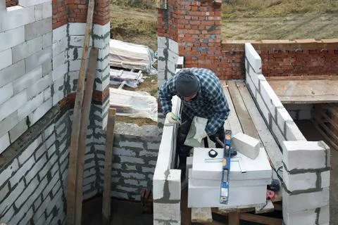 The master, using a trowel, glues gasblocks with a glutinous solution at the  스톡 사진