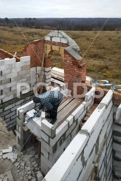 The master, using a trowel, glues gasblocks with a glutinous solution at the Stock Photos
