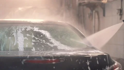 Master washes the foam from the black sedan with a hose with water Stock Footage 153172268