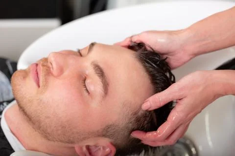 Master washes the head of the client in the Barber shop, hairdresser makes Stock Photos