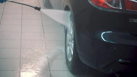 Master washes wheel, cap of sedan with hose with water in service closeup rare Stock Footage 155965366