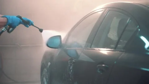 Master washes window, door,mirror of sedan with water hose in service closeup Stock Footage 155965423