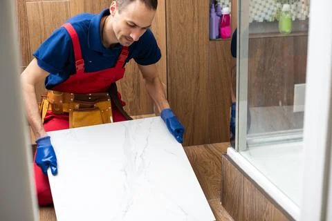 Master is wearing work clothes, is checking horizon of installing tiles, using Stock Photos