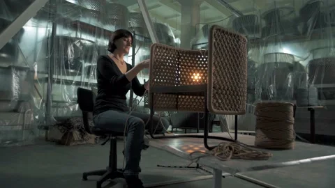Master weaver creates a stylish chair for the exterior of a furniture factory Stock Footage 179705400