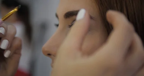 Master with white manicure aligns pretty lady eyeshadows Stock Footage 124258535