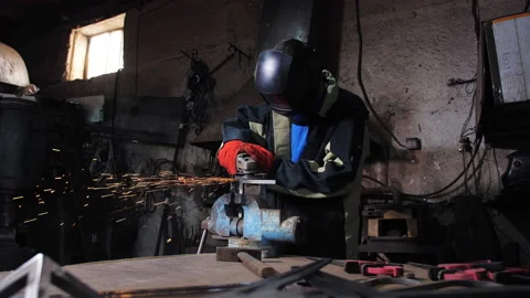 A master in work clothes grinding with a grinding machine a metal angular Stock Footage 205065281