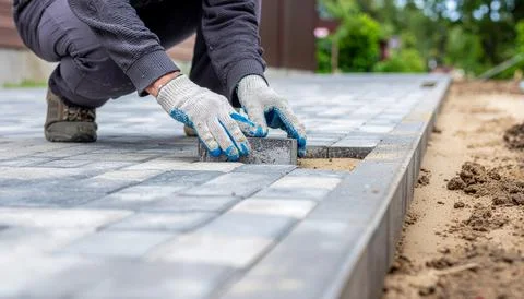 The master in work gloves lays paving stones in layers Stock Photos