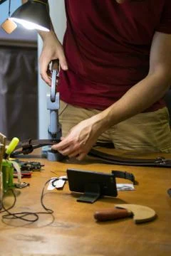 Master is working on press with skin. Creating a belt made of genuine leather Stock Photos