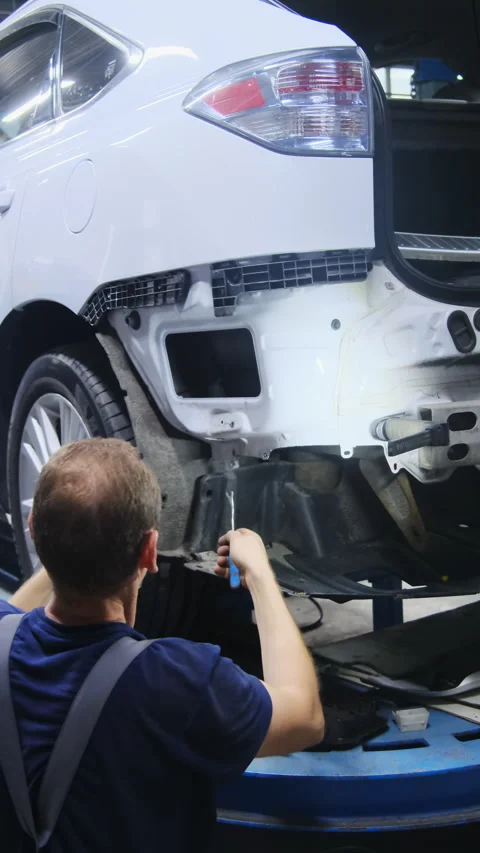 Master works on components of car bumper in large hall Stock Footage 317652475