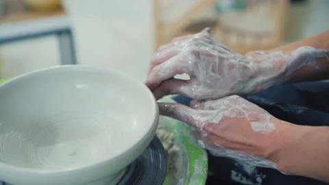 Master works on potter's wheel, doing blank.Girl makes pottery from clay Stock Footage 172506044