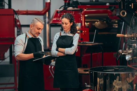Master writing notes about the quality of the beans. Roastery machine backgro Stock Photos