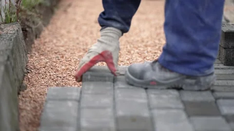 The master in yellow gloves lays paving stones in layers on sidewalk construc 库存影片 330119644