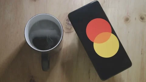 Mastercard logo on an Android smartphone with a hot cup of coffee Stock Footage 157275050