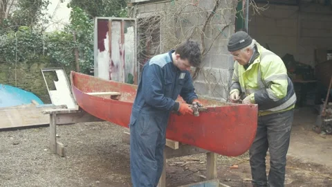 Mastercraftsman teaching an apprentice boat repair Stock Footage 235890177