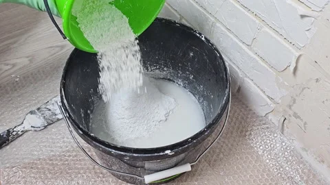 The master's hand stirs the plaster, cement in a bucket with a spatula Stock-Footage 238541551