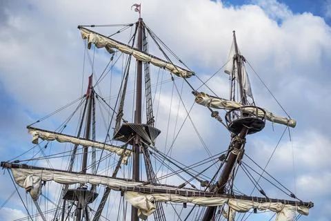 Masts and rigging of old pirate ship on background of cloudy blue sky Stock Photos