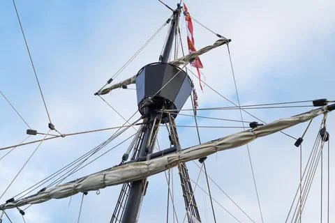 Masts and rigging of old pirate ship on background of cloudy blue sky Foto stock