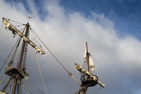 Masts and rigging of old pirate ship on background of cloudy blue sky Stock Photos