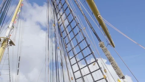 Masts of sail vessel on blue sky background. Rope ladder to the main mast of Stock Footage